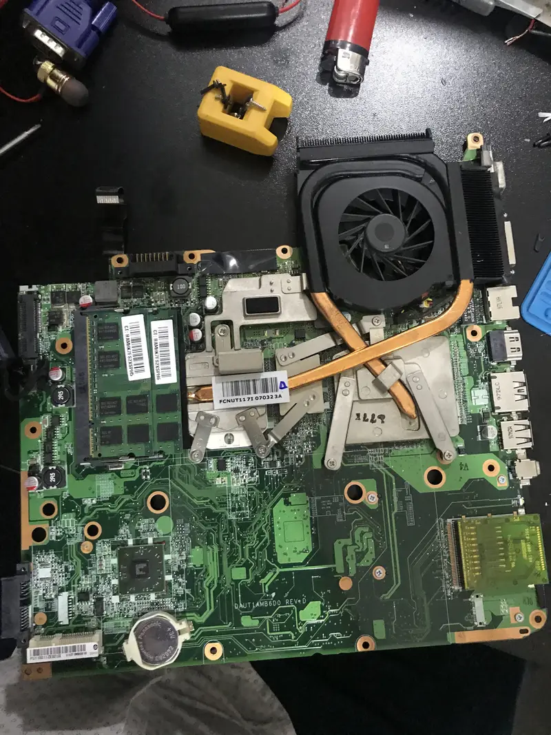 Sökülmüş laptop anakartı, fanı ve bakır ısı borusu; termal macun bakımı öncesi